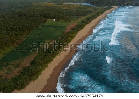 Drone view of ocean rip current, beach with waves in Java at sunset