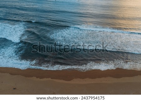 Drone view of ocean rip current, beach with waves in Java at sunset