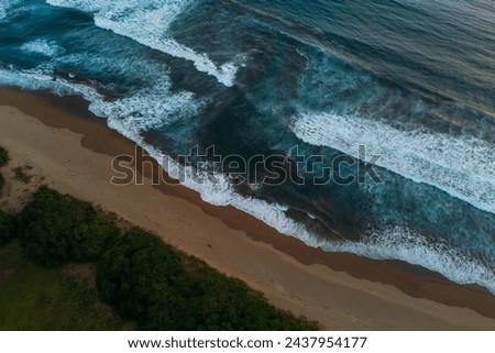 Drone view of ocean rip current, beach with waves in Java at sunset