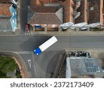 Drone view of a public bus seen making a sharp turn into the high street of a typical English town. The road is narrow and the vehicle needs to turn hard.