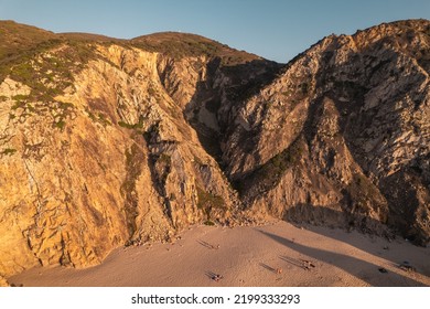 Drone View Of Rough Rocks Located Near Sandy Beach With Tourists In Sunny Morning On Resort