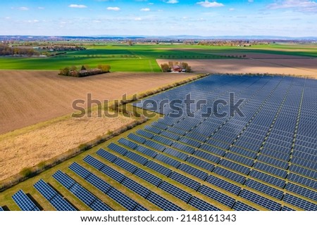 A drone view of a solar park with photovoltaic panels next to fields and a farm 商業照片 © 