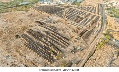 Drone view of stacked waste windrows laid out across a legacy dump recycling site