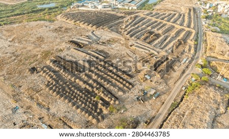 Drone view of stacked waste windrows laid out across a legacy dump recycling site