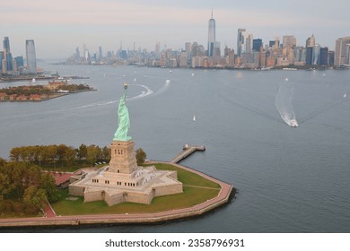 A drone view of the Statue of Liberty on Liberty Island surrounded by water at sunset in New York Harbor, New York City, USA