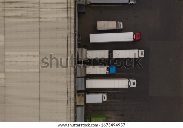 drone view of trucks and storage warehouse during\
summer day.