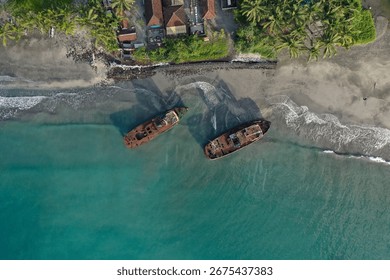 Drone view of two rusty abandoned ships near ocean shore