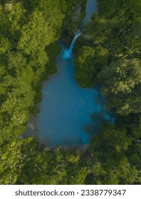 Drone view of a waterfall falling into a lake surrounded by a rainforest