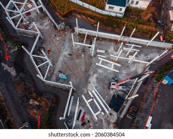 Drone view of working tower cranes and a construction site with machines, vehicles and workers. Building substructure