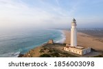 Drone views of the Trafalgar Lighthouse on the Costa de la Luz in Caños de Meca, Cadiz Andalucia, Spain. Faro de Trafalgar from above on a beautiful day with clouds and the blue sea.