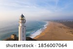 Drone views of the Trafalgar Lighthouse on the Costa de la Luz in Caños de Meca, Cadiz Andalucia, Spain. Faro de Trafalgar from above on a beautiful day with clouds and the blue sea.
