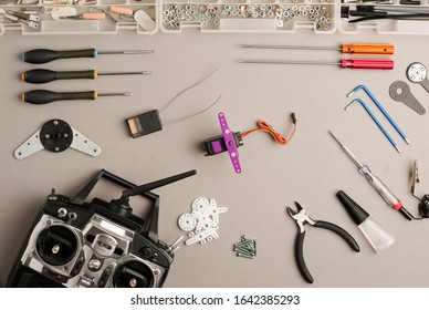 Drone workshop table, with aero model radio control (RC), drone parts, and tools on the gray worktable. Top view