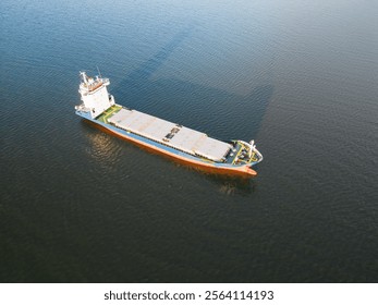 A drone's eye view of an empty cargo ship sailing the calm sea after unloading. Maritime transport, logistics, international trade, import, export, freight, global economy, shipping.