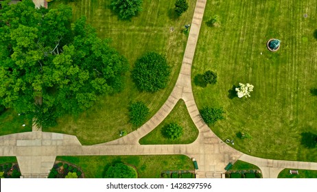 A Drone's Eye View Of A Walkway With Freshly Mowed Green Lawn And Luscious Green Trees