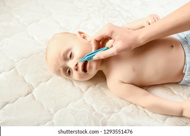 Drooling Sick Baby With A Cold And Running Nose Getting Wiped By Mom's Hand, Lying Naked In White Sheets. Infant Nappy Change And Skin Care.