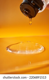 A Drop Of Body Gel Or Shampoo Pouring From Above On A Yellow Saturated Background.