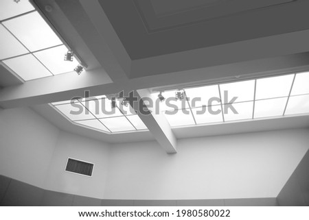 Drop ceiling with frames and lamps. Abstract modern business architecture. Interior of commerical real estate. Office building. Regular geometrical background featuring girders and rectangular tiles