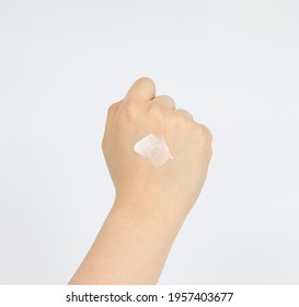 A Drop Of Cosmetic Cream On The Back Of Woman's Clenched Right Hand.