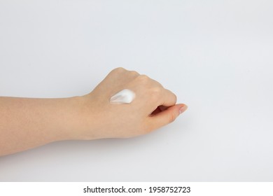 A Drop Of Cosmetic Cream On The Back Of Woman's Clenched Left Hand.