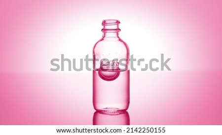 Drop falls down into medical bottle with pink transparent liquid on pale pink background | Abstract body care cosmetics with lactic acid formulating concept