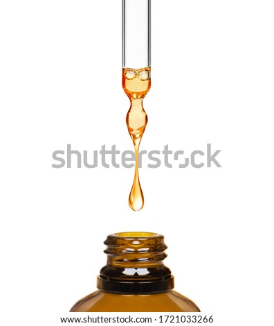 Drop falls from a pipette in a medical bottle close-up, isolated on a white background