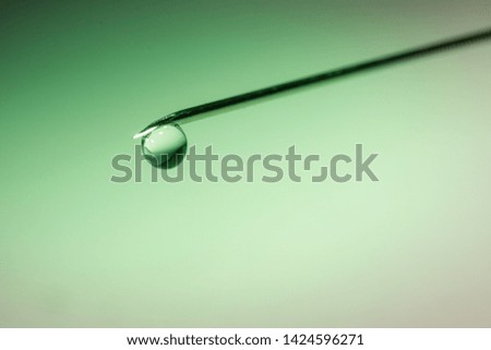 drop of fluid on the tip of a syringe needle 