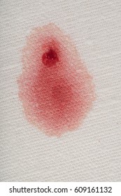 Drop Of Fresh Red Blood With A Clot And Stain Soaked In On A White Cotton Cloth.  It's A Closeup Vertical Photo That Can Be A Horizontal.