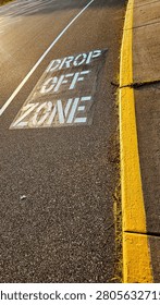 Drop off zone painted stencil sign text on asphalt lane pavement road street pavement near sidewalk yellow curb. transportation design element.