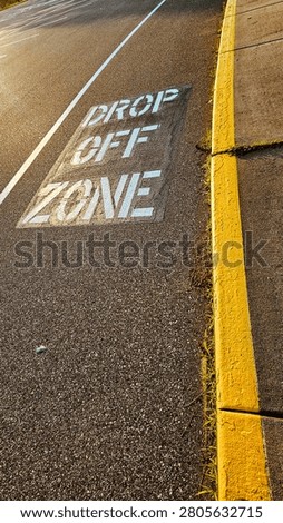 Drop off zone painted stencil sign text on asphalt lane pavement road street pavement near sidewalk yellow curb. transportation design element.