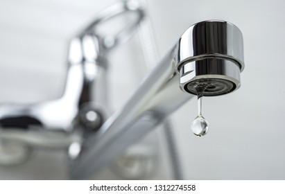 A drop of pure water dripping from the tap. Selective focus. - Shutterstock ID 1312274558