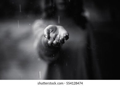 A drop of rain falls on a woman hand - Shutterstock ID 554128474