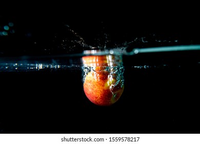 Drop Red Apple In Tank. Water Is Splash On Black Background