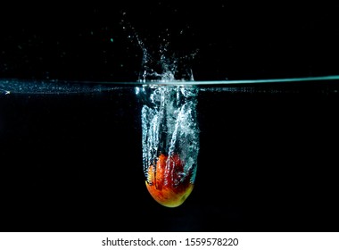 Drop Red Apple In Tank. Water Is Splash On Black Background