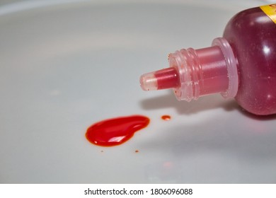 A Drop Of Red Food Dye From A Plastic Bottle On A White Plate 