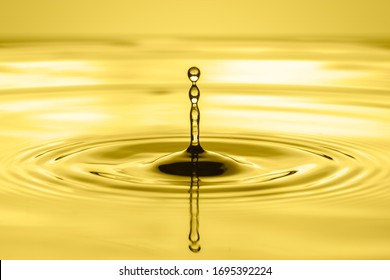 Drop Of Vegetable Oil Or Engine Oil Water And Ripple On Golden Background
