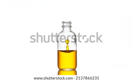 Drop of vitamin C is falling down into clear medical bottle with yellow transparent liquid on white background | Abstract skincare cosmetics with vitamin C formulation concept