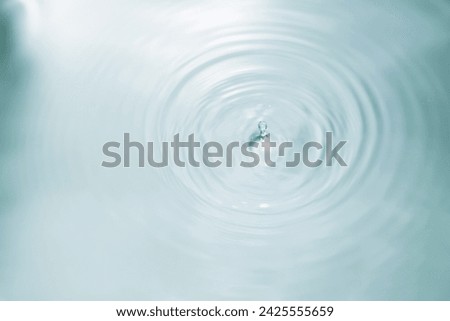 Drop of water falling into water with ripples and a blurred background