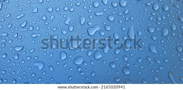 A drop of water on the hood of\
the car. Water beads after rain or car wash on blue paint\
surface