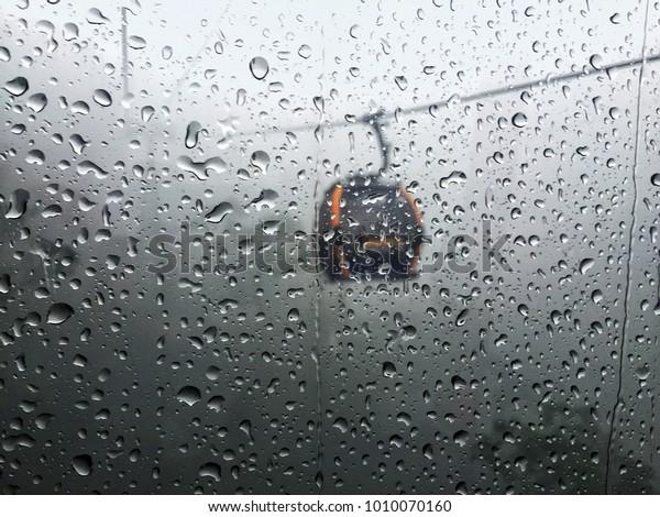 Droplet of heavy\
rain on window of cable\
car