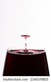 Droplet of red wine falling in a glass isolated on white close up