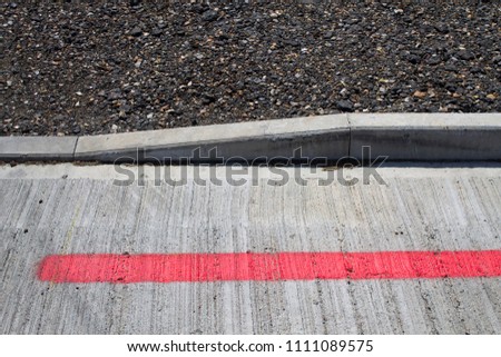 Dropped kerb from asphalt car park with red painted line
