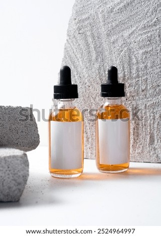 A dropper bottle mockup featuring a clean white label, placed on a white stone background in a minimalist and modern photography style. This image is perfect for cosmetic or skincare product mockups