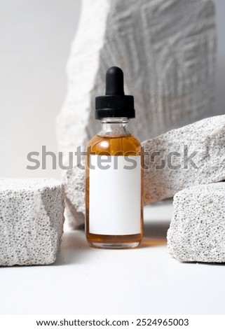 A dropper bottle mockup featuring a clean white label, placed on a white stone background in a minimalist and modern photography style. This image is perfect for cosmetic or skincare product mockups