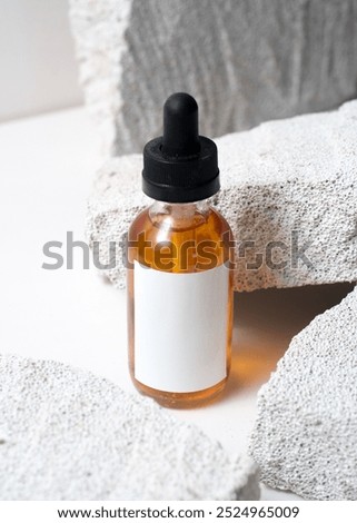 A dropper bottle mockup featuring a clean white label, placed on a white stone background in a minimalist and modern photography style. This image is perfect for cosmetic or skincare product mockups