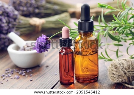 Dropper bottles of lavender essential oil, fresh and dried lavender flowers on background.