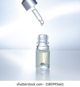 Dropper glass bottle with falling drop of cosmetics. cosmetic pipette on a light background. Premium Photo