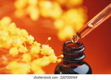 Dropper pipette with serum or oil and amber bottle. Skincare products, natural cosmetic and yellow flowers on orange background. Beauty concept for face and body care. - Shutterstock ID 2207205969