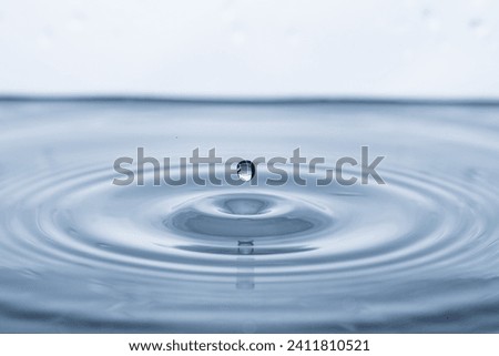 The dropping droplet into pure clear water on a white background up close