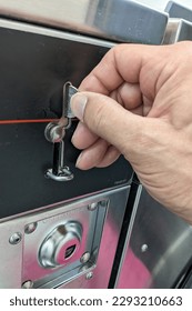 Dropping a quarter into a laundry machine photographed up close.
