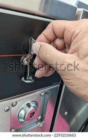 Dropping a quarter into a laundry machine photographed up close.